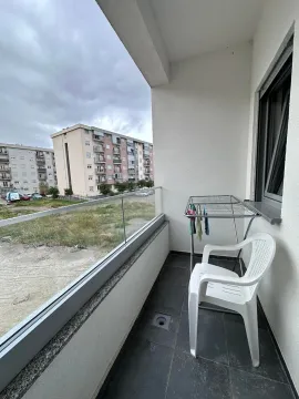 Small covered balcony with a glass railing and a view of buildings. - image 8