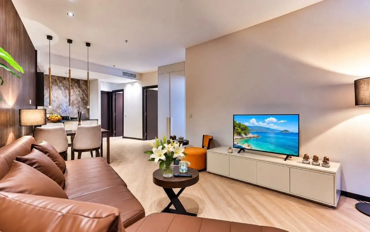 Living room with sofa, television, and dining area in the background.