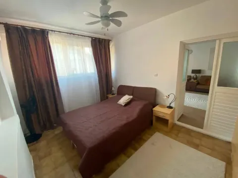 Spavaća soba sa bračnim krevetom, prozorom sa braon zavjesama i izlazom u drugu prostoriju. - image 11