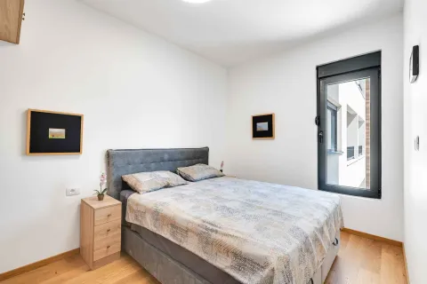 Uređena spavaća soba sa bračnim krevetom, noćnim stočićem i prozorom. - image 10