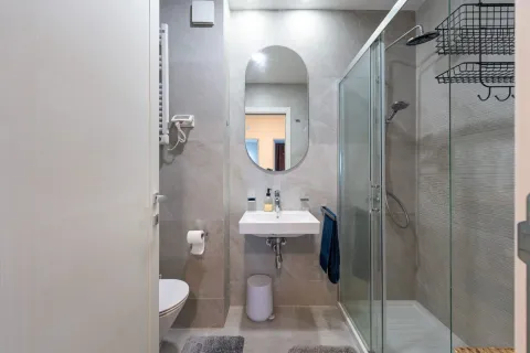 Modern bathroom with a shower cabin, washbasin, and toilet. - image 13