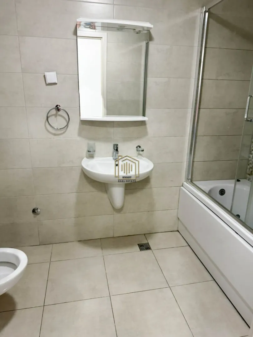 Bathroom equipped with a washbasin, mirror, bathtub, and toilet.