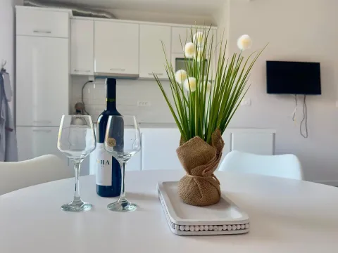 Trpezarijski sto sa flašom vina i ukrasnom biljkom u pozadini kuhinje. - image 6