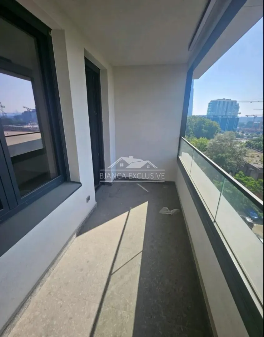 Nenamešten balkon sa staklenom ogradom i pogledom na okolinu.