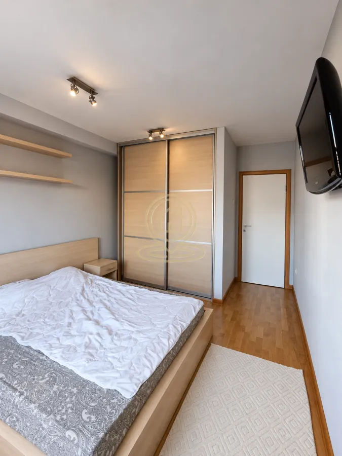 Modern bedroom with a double bed, built-in wardrobe, and wall-mounted TV.