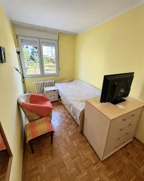 Small bedroom with a bed, an armchair, and a dresser with a TV. - image 6