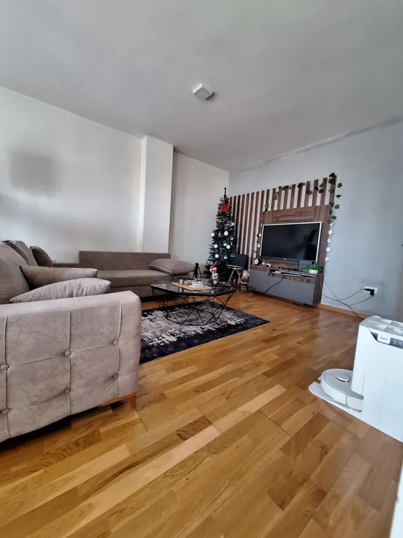 Dnevna soba sa garniturom, stočićem i televizorom.