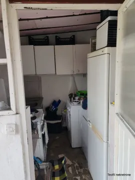 Pogled na manju kuhinju sa bijelim elementima i frižiderom. - image 14