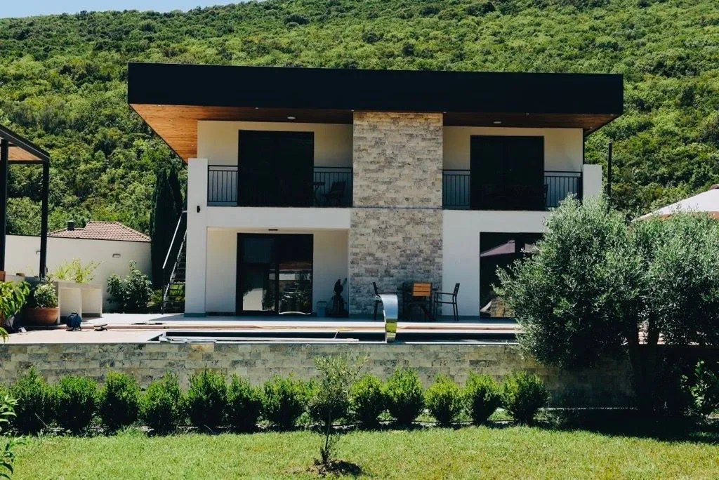 Eksterijer moderne dvospratne kuće sa bazenom i dvorištem.
