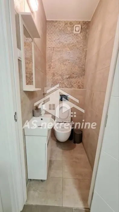 Manje kupatilo sa WC šoljom, umivaonikom i ogledalom.