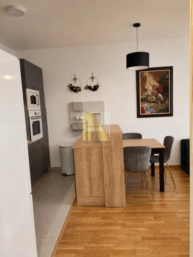 Moderna kuhinja sa šankom i trpezarijom u sklopu dnevnog boravka.