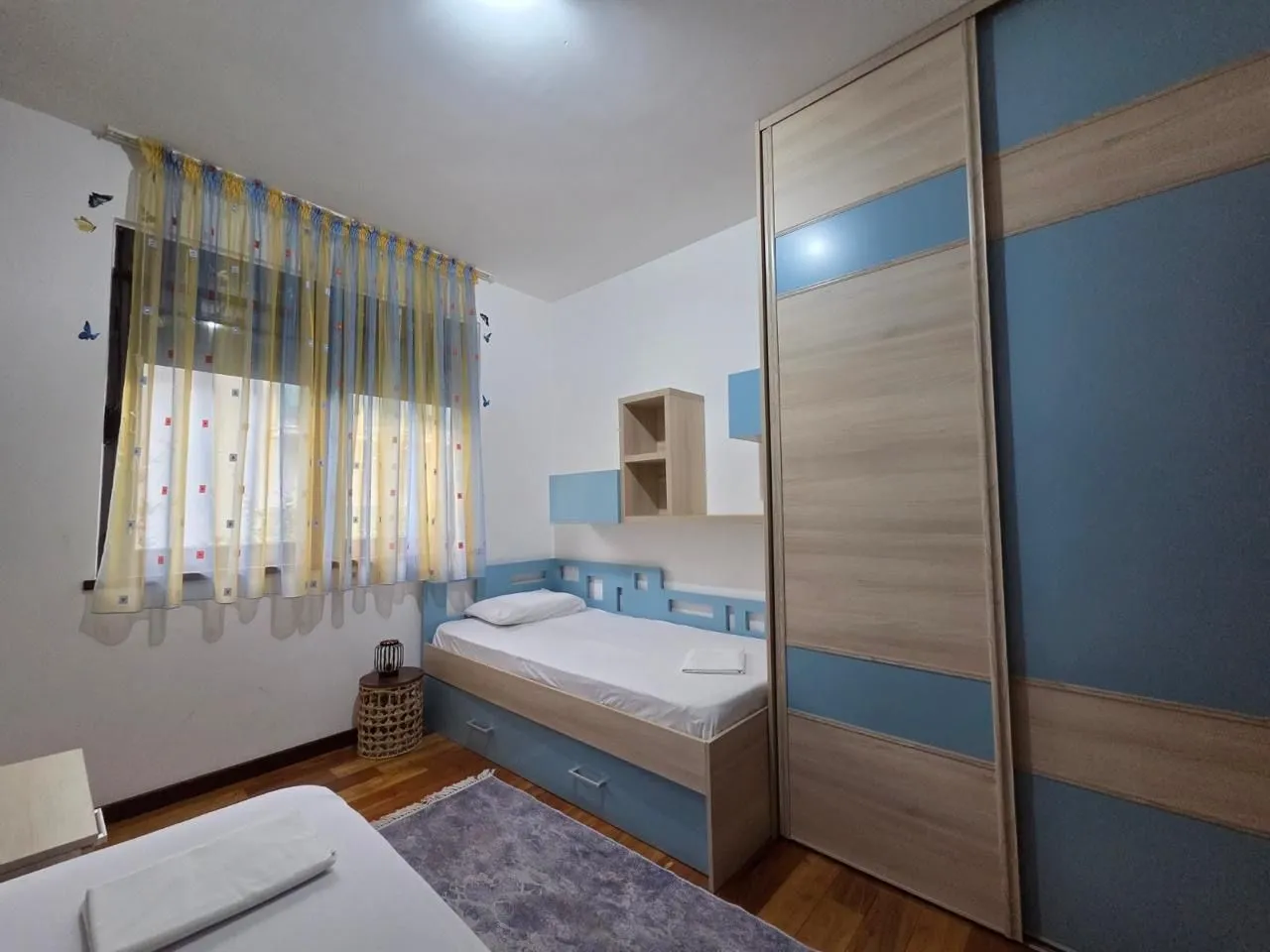 Children's bedroom with a bed, large wardrobe, and a window.