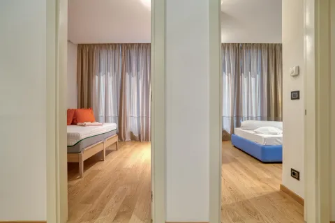 View from the hallway into two furnished bedrooms. - image 9