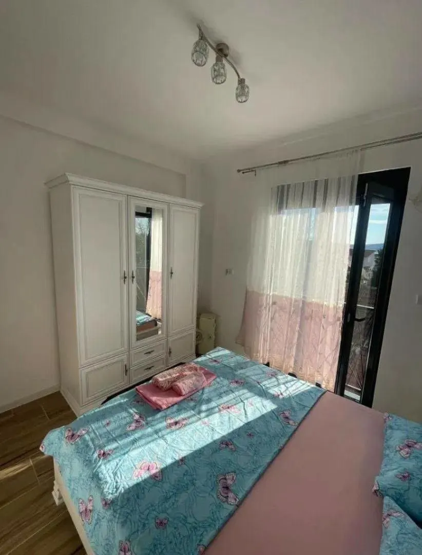 Spavaća soba sa velikim bračnim krevetom, bijelim garderoberom i izlazom na terasu.