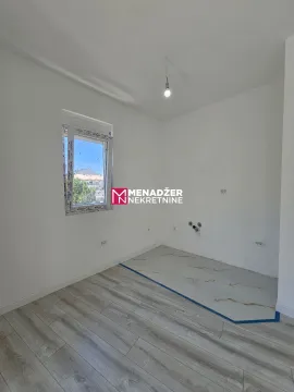 Prazna prostorija sa bijelim zidovima i kombinacijom laminata i pločica na podu. - image 4