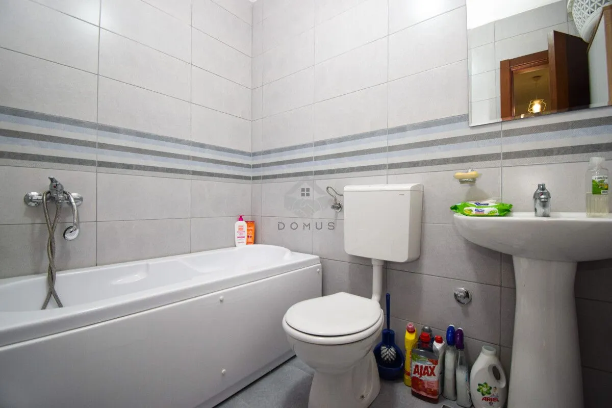 Bathroom equipped with a bathtub, washbasin, and toilet with tiled walls.