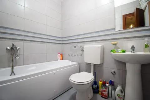 Bathroom equipped with a bathtub, washbasin, and toilet with tiled walls. - image 9