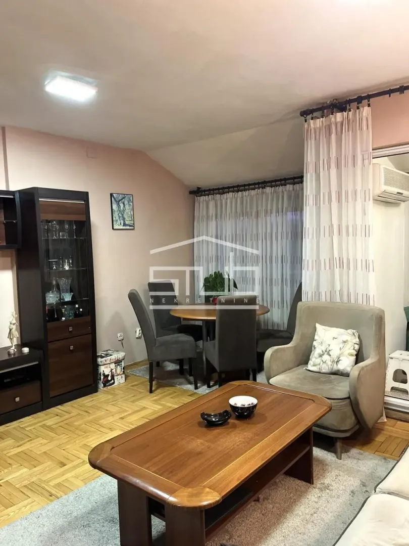 Dnevni boravak sa garniturom, stočićem i trpezarijskim stolom u uglu.