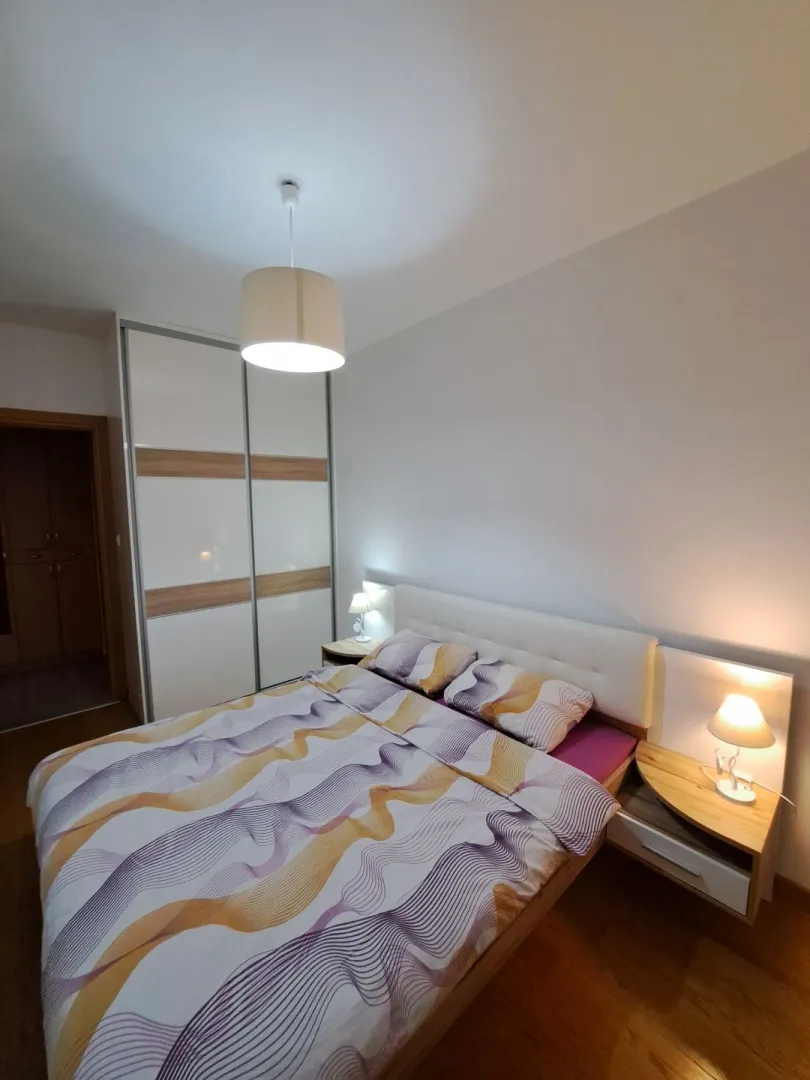 Uređena spavaća soba sa bračnim krevetom, garderoberom i noćnim stočićima sa lampama.