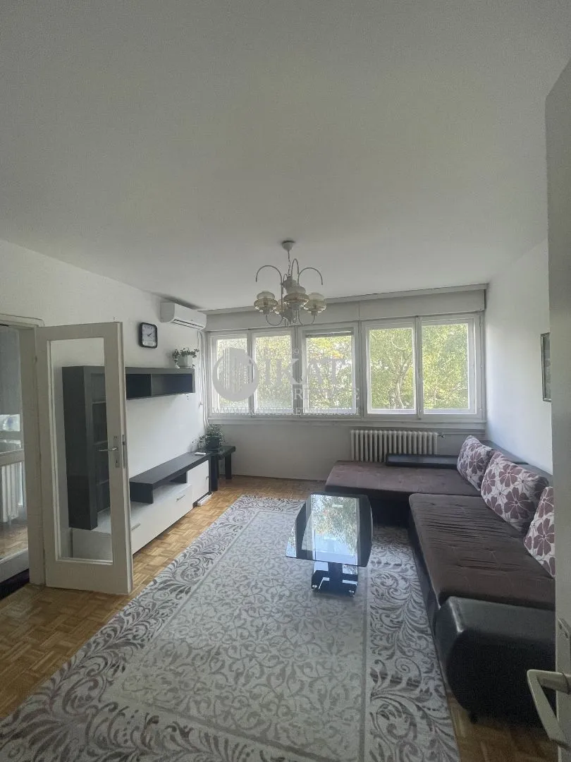 Living room with a sofa, coffee table and large windows.
