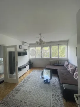 Living room with a sofa, coffee table and large windows. - image 2