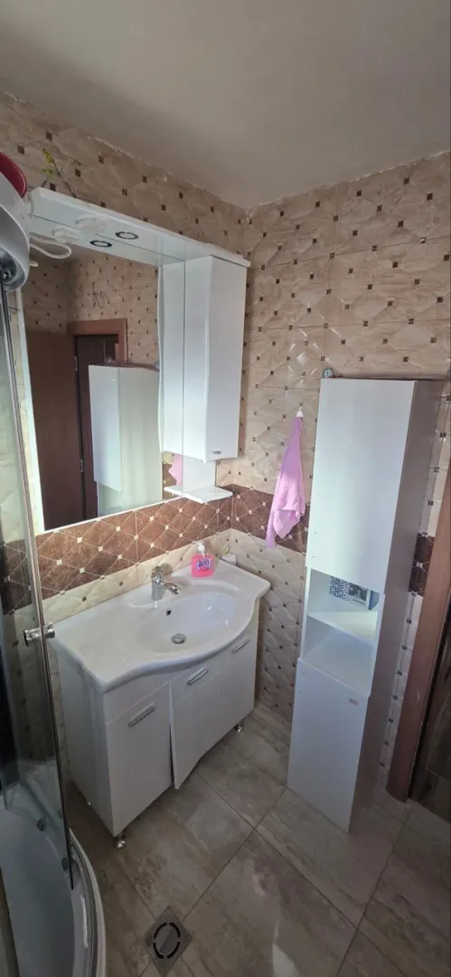 Small bathroom with a sink, mirror, and white cabinetry.