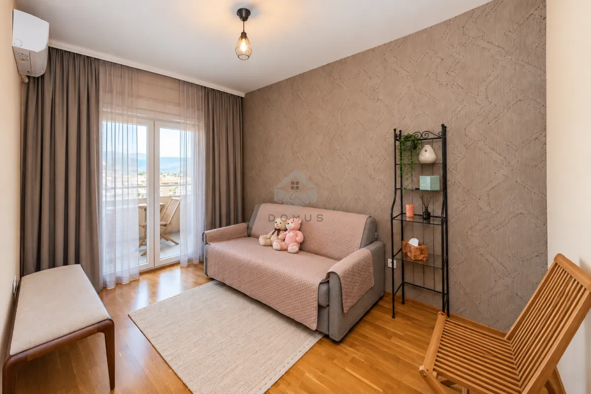 Living room with a sofa, shelving unit, and balcony access.