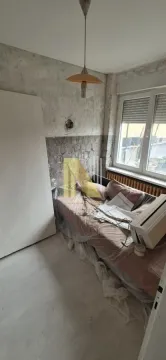Manja soba sa krevetom prekrivenim zaštitnom folijom tokom renoviranja. - image 11