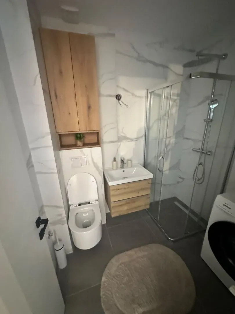 Moderno opremljeno kupatilo sa tuš kabinom, WC šoljom i umivaonikom.