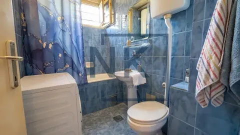 Kupatilo obloženo pločicama sa kadom, umivaonikom, WC šoljom i mašinom za veš. - image 5