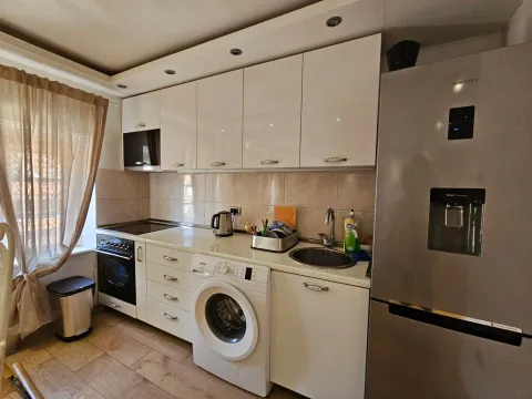 Kuhinja sa bijelim elementima, ugrađenim kućnim aparatima i frižiderom. - image 9