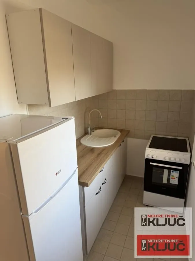 Manja kuhinja sa frižiderom, šporetom i sudoperom.