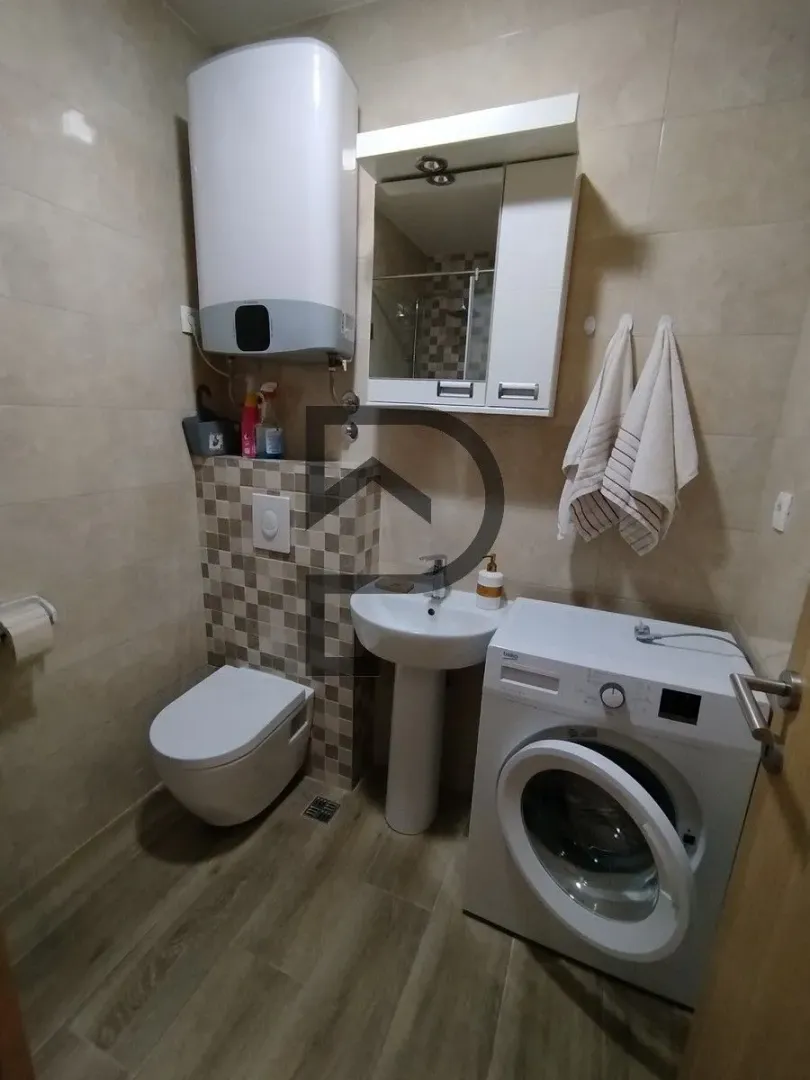 Small bathroom with toilet, washbasin, and washing machine.