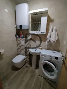 Small bathroom with toilet, washbasin, and washing machine. - image 9
