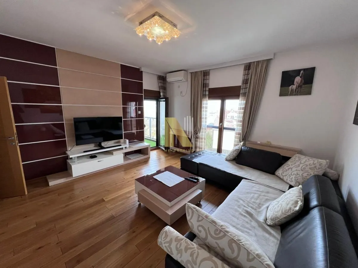 Dnevna soba sa garniturom, TV-om i izlazom na terasu.