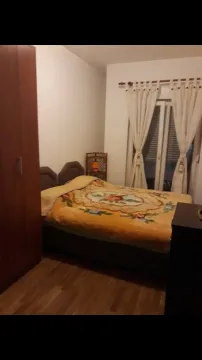 A simple bedroom featuring a double bed and a wooden wardrobe. - image 7