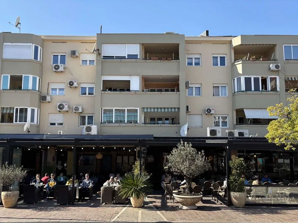 View of the building facade with commercial space on the ground floor and terraces.