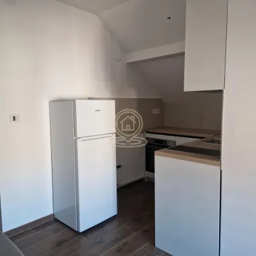 Small kitchen with white cabinets and a refrigerator in an attic space. - image 9