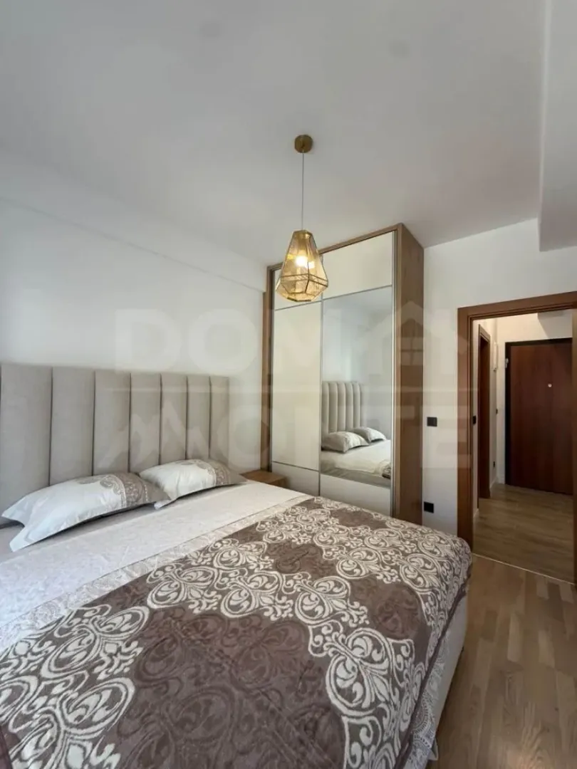 Furnished bedroom with a double bed, wardrobe, and a pendant light.