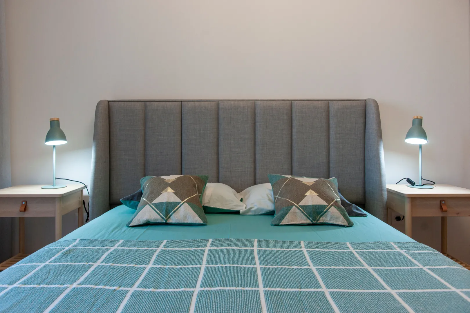 Double bed with a padded headboard, pillows, and bedside tables with lamps.