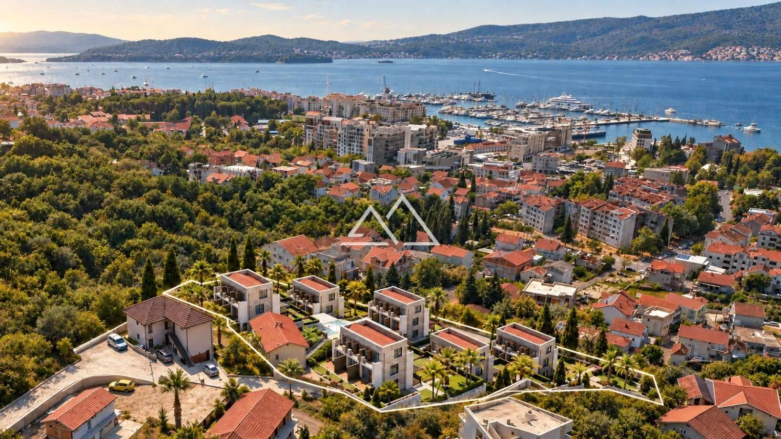 Pogled iz vazduha na kompleks zgrada sa pogledom na more i marinu.