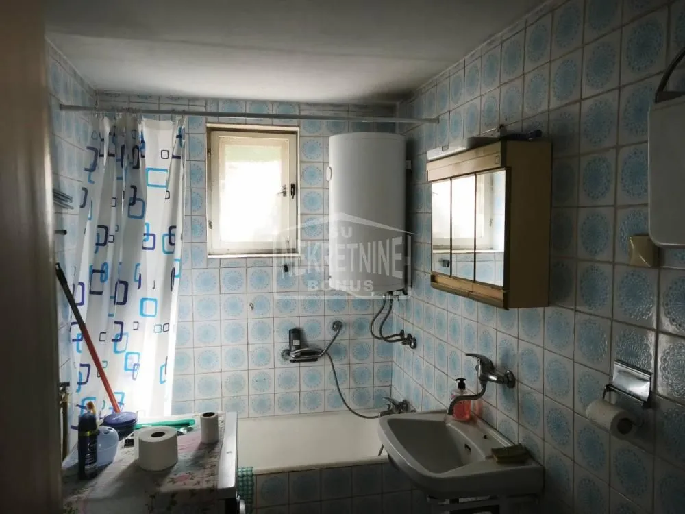 Manje kupatilo sa kadom, umivaonikom i zidnim pločicama.