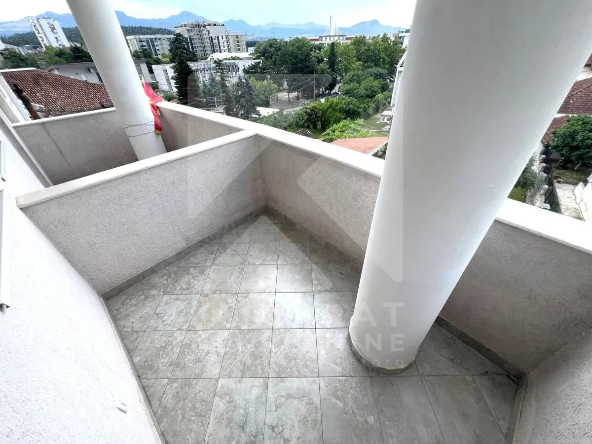 Nenamješten balkon sa stubovima i pogledom na grad.
