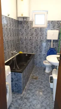 Simple bathroom with blue tiles, a bathtub, and a washing machine. - image 6