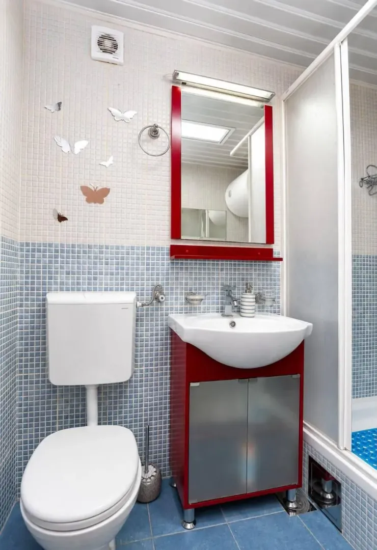 Bathroom with a toilet, washbasin, mirror and shower cabin.