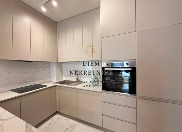 Modern kitchen with built-in appliances and marble countertops.