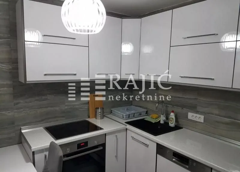 Modern kitchen with white cabinets and built-in appliances.