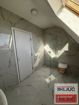 Moderno kupatilo sa mermernim pločicama, tuš kabinom i krovnim prozorom. - image 4