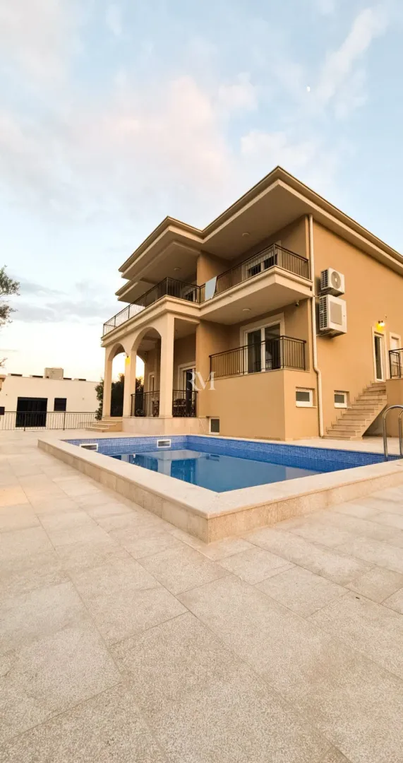 Exterior of a two-story house with a swimming pool and paved yard.