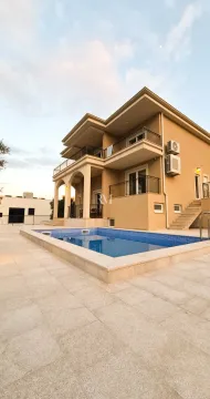 Exterior of a two-story house with a swimming pool and paved yard. - image 5